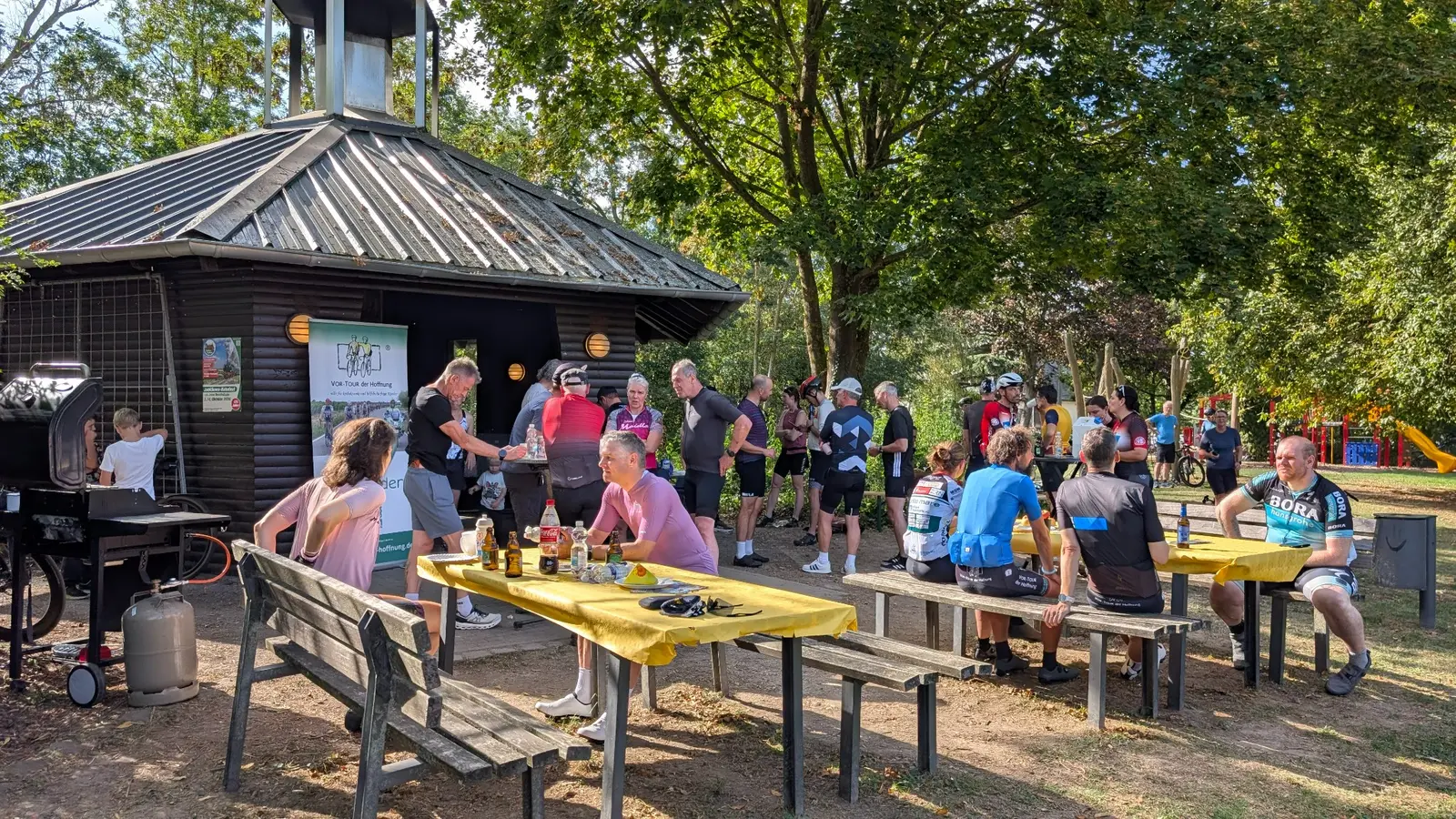 Menschen und Fahrräder rund um die Grillhütte